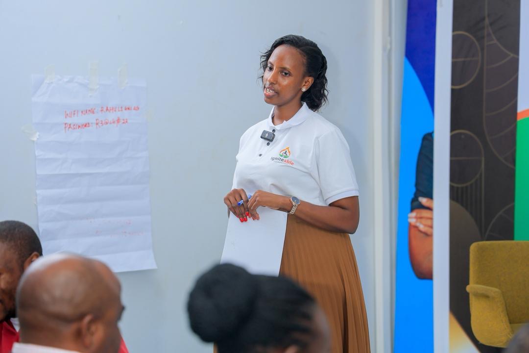 A facilitator in an Igniteable Foundation polo shirt leads a training session beside a flip chart.