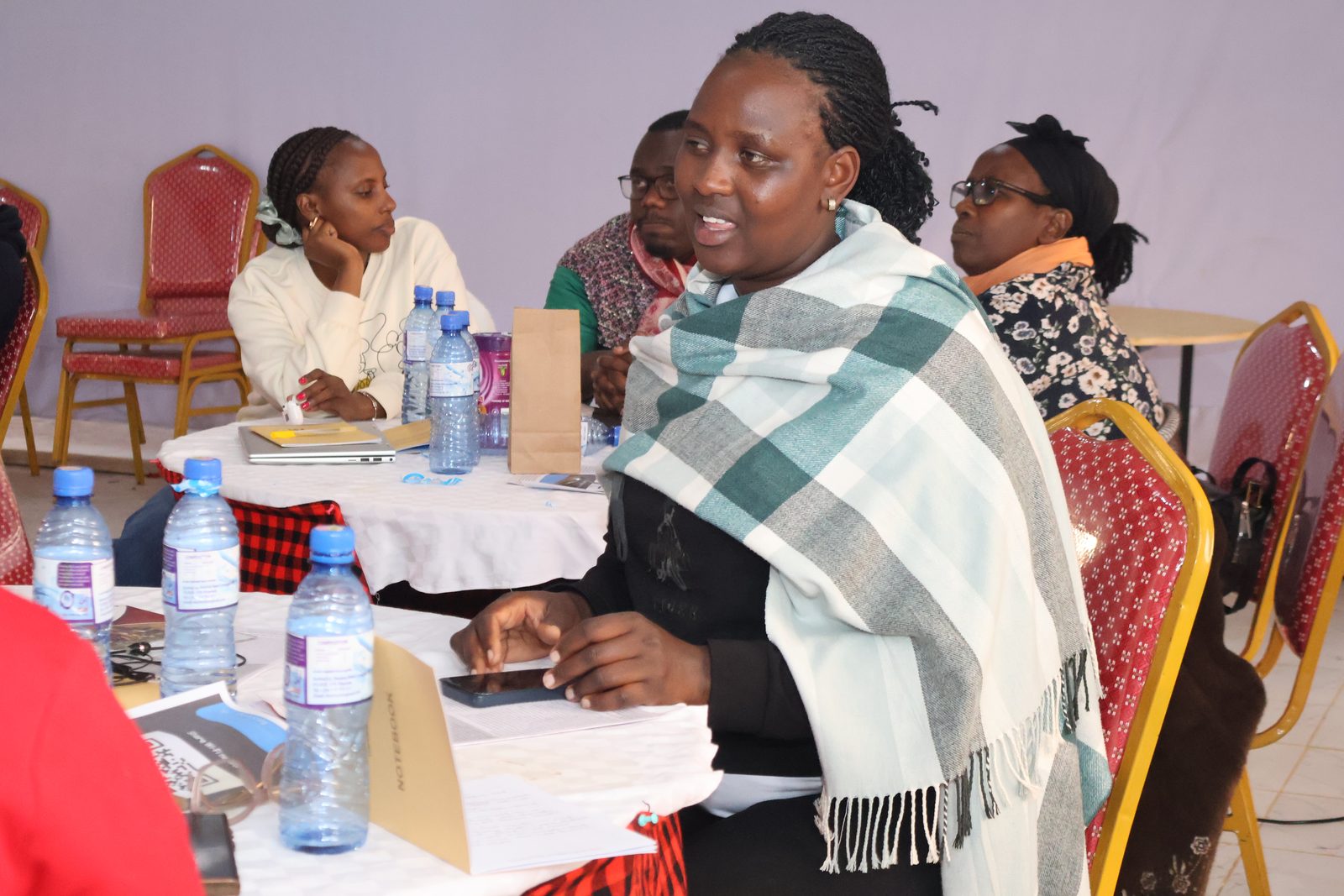 A participant makes a point during a group discussion as others listen around the table.